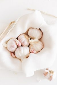 five garlic on white textile - 13 medicinal benefits of garlic