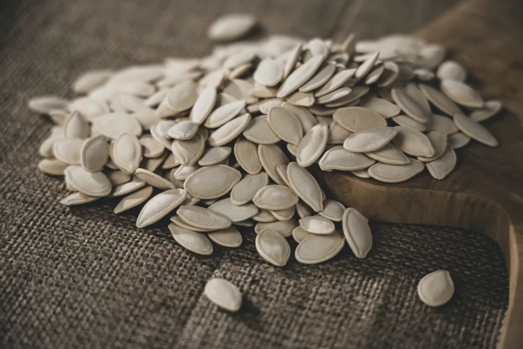 brown seeds on brown wooden surface, pumpkin seeds, super seeds, health benefits of pumpkin seeds