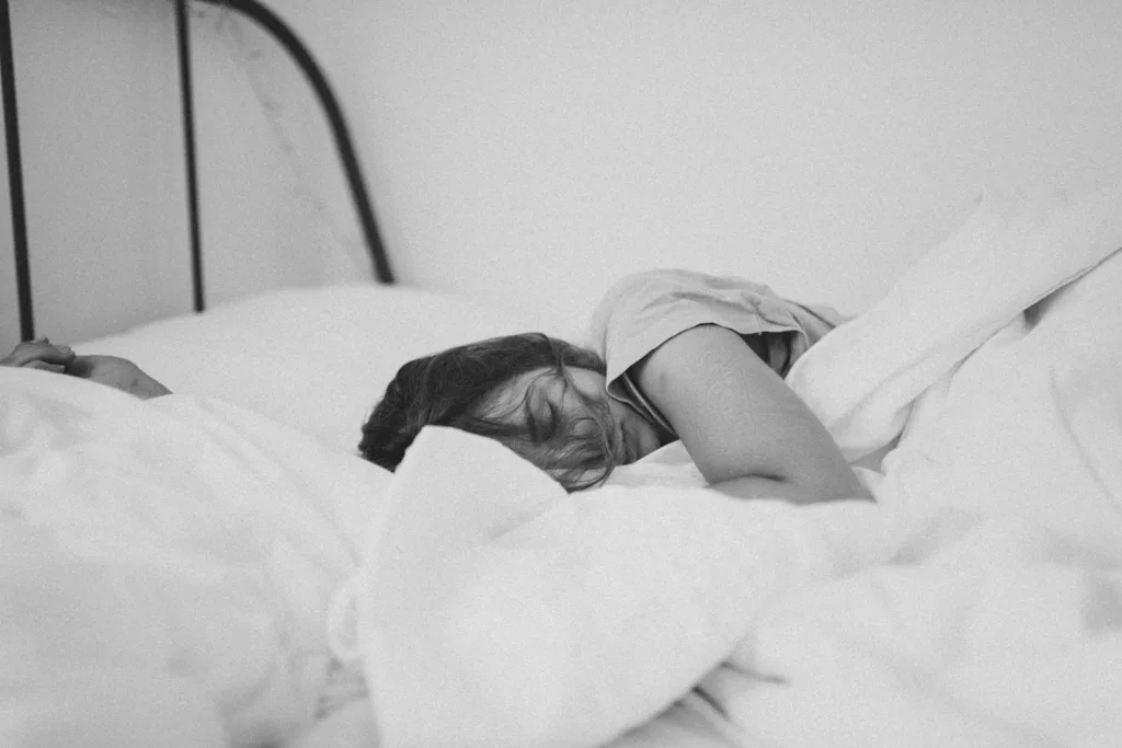 grayscale photo of sleeping woman lying on bed, sleeping is one of the ways to avoid acid reflux