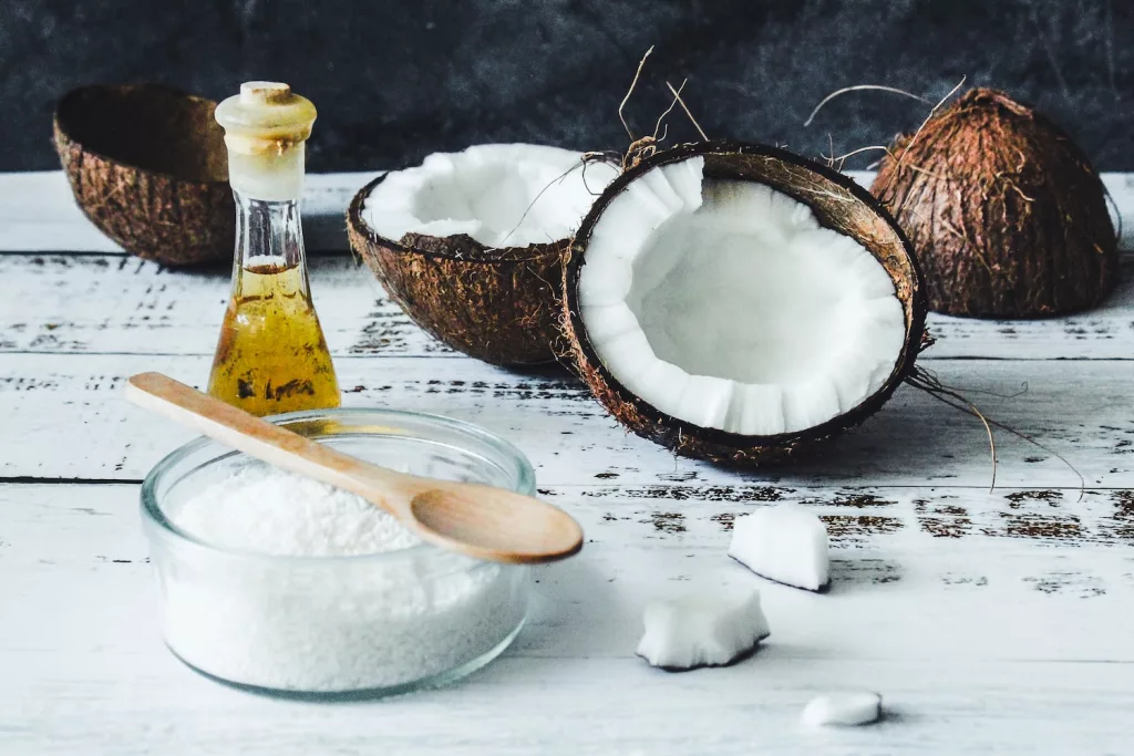 white powder in clear glass jar beside brown wooden spoon, coconut oil as one of the natural remedies to relieve skin itches