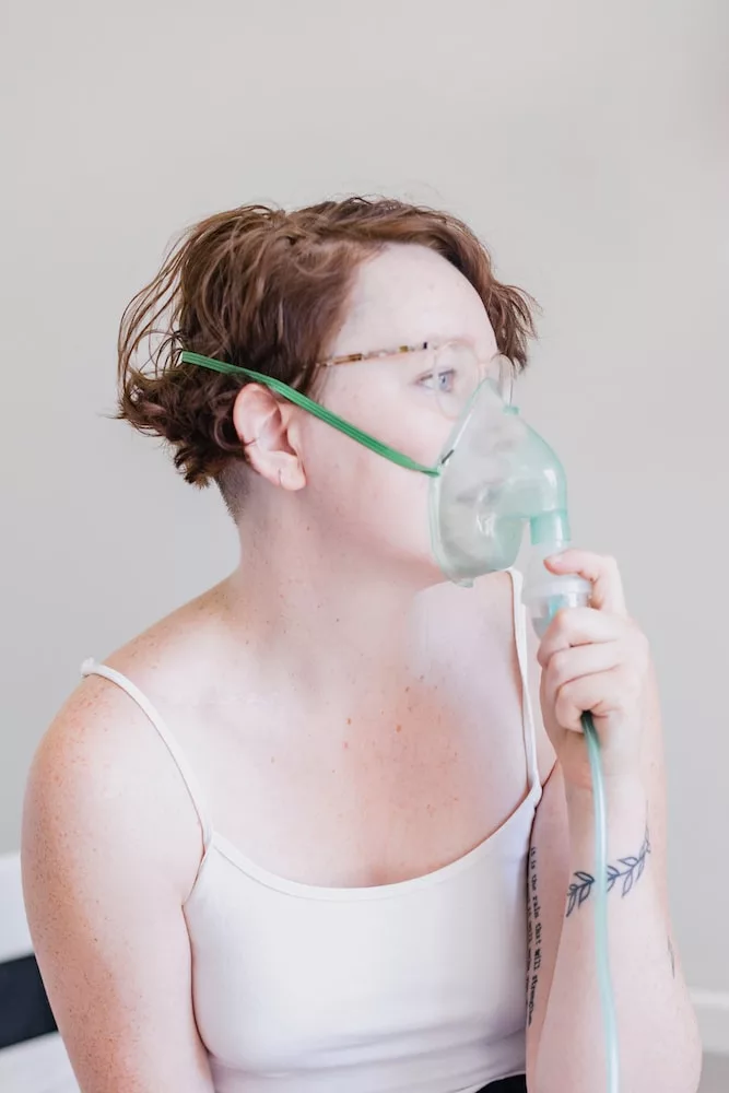 a woman in a white tank top with a mask on her face, signs and symptoms of asthma