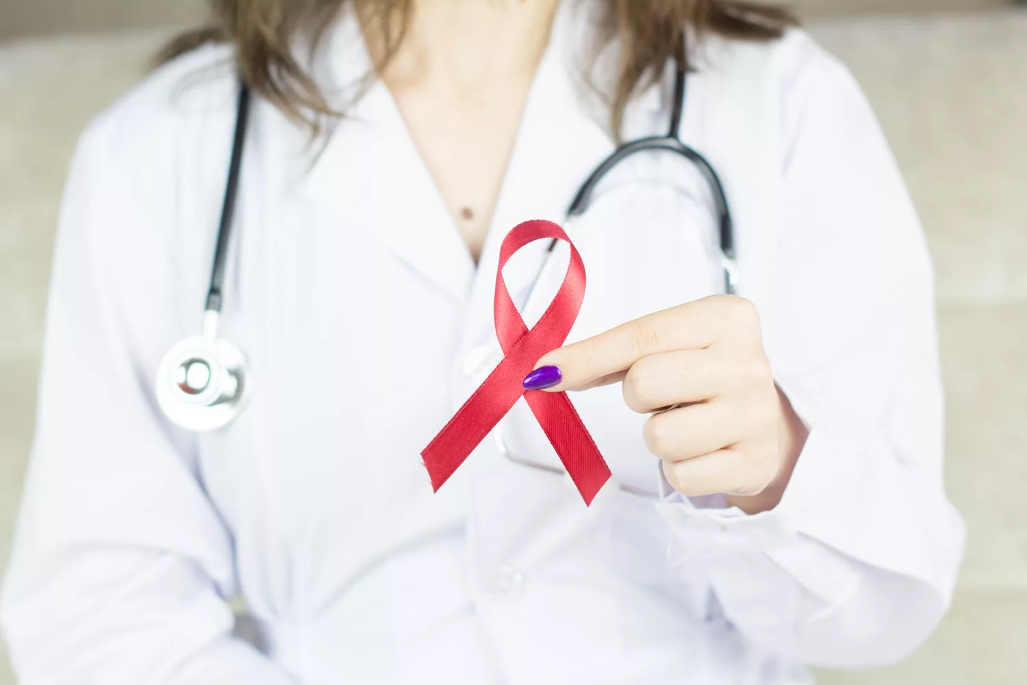 a woman in a white shirt holding a red ribbon, cancer signs women often ignore
