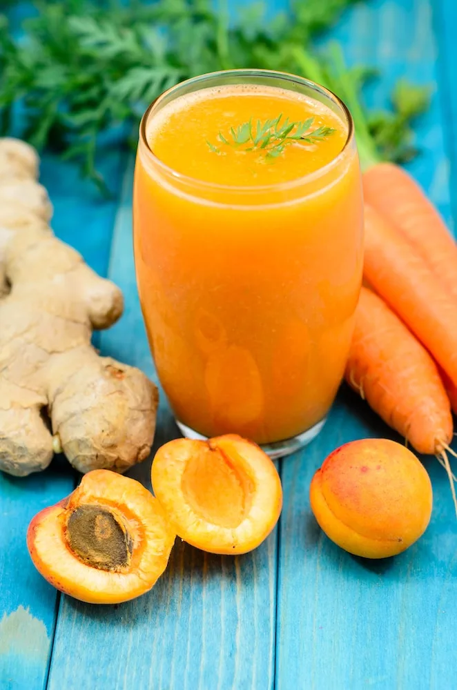 clear drinking glass besides carrots, carrot and ginger juice