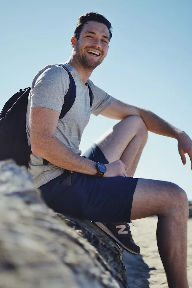 smiling man sitting on gray rock at daytime, health tips for men