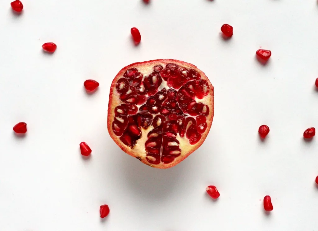 red sliced fruit on white surface, health benefits of pomegranate