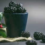 Home 11 A ceramic cup filled with fresh blackberries, showcasing their freshness and vibrant color.
