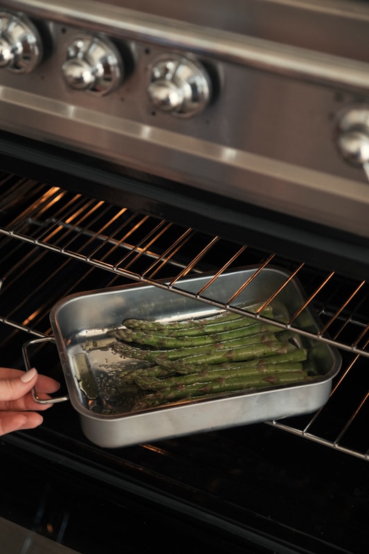 Asparagus Benefits for Digestion: A Green Spear for a Happier Gut 3 Hand places pan of asparagus into oven.