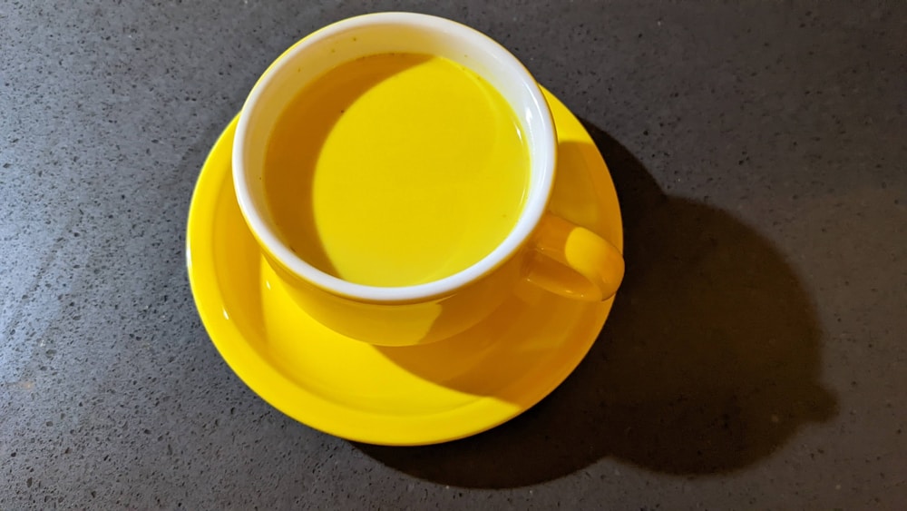 a cup of tea sits on a yellow saucer | turmeric milk recipe for cold and cough