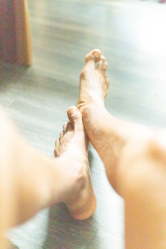 a close up of a person's bare feet on a wooden floor | best remedy for cracked heels