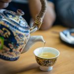 a teapot pouring tea into a cup | basil tea health benefits